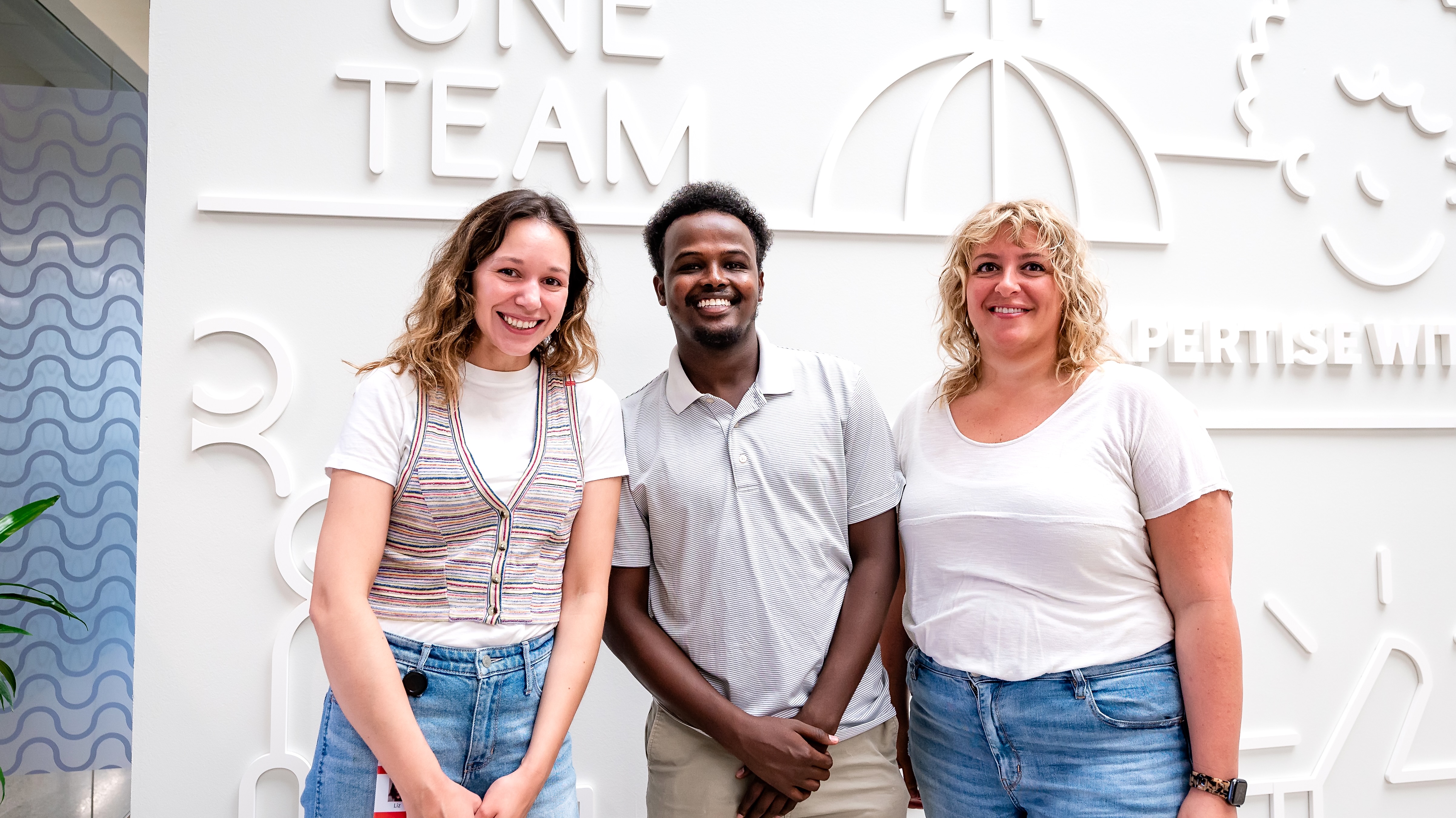 Three toast employees in white shirts standing in front of a white sculpture wall