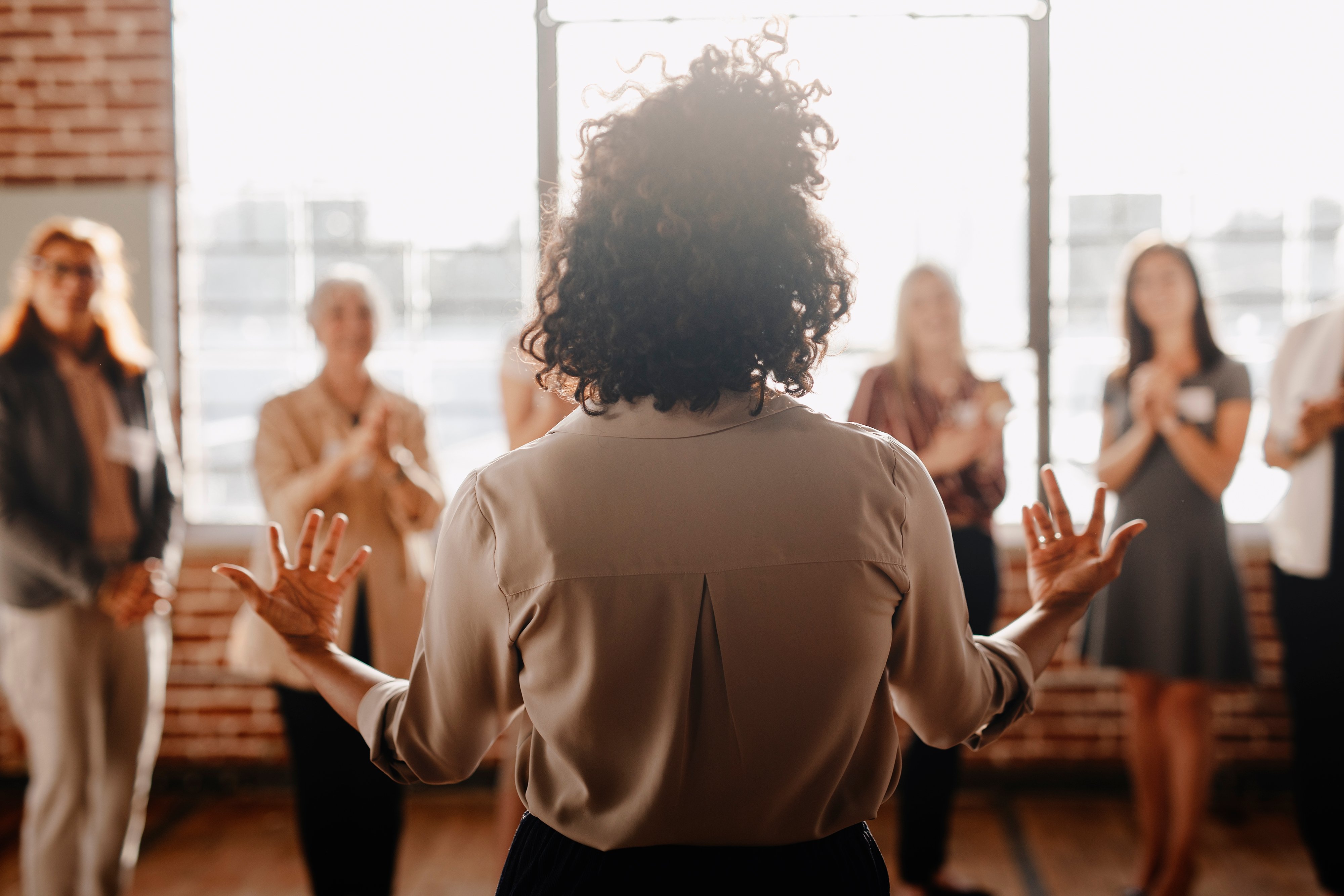 A leader faces four clapping team members.