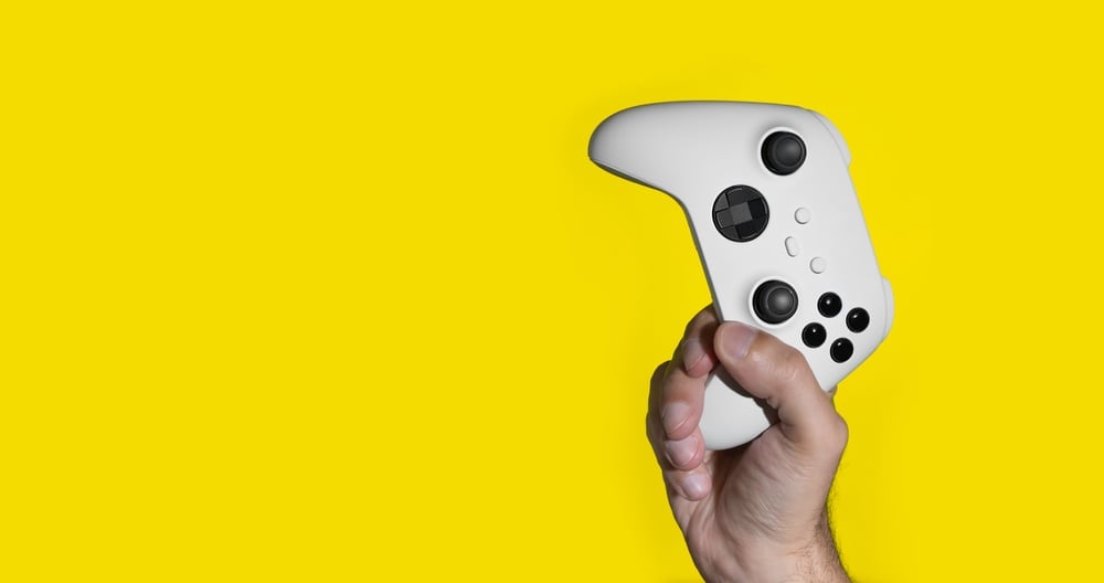 xbox controller in hand on yellow background
