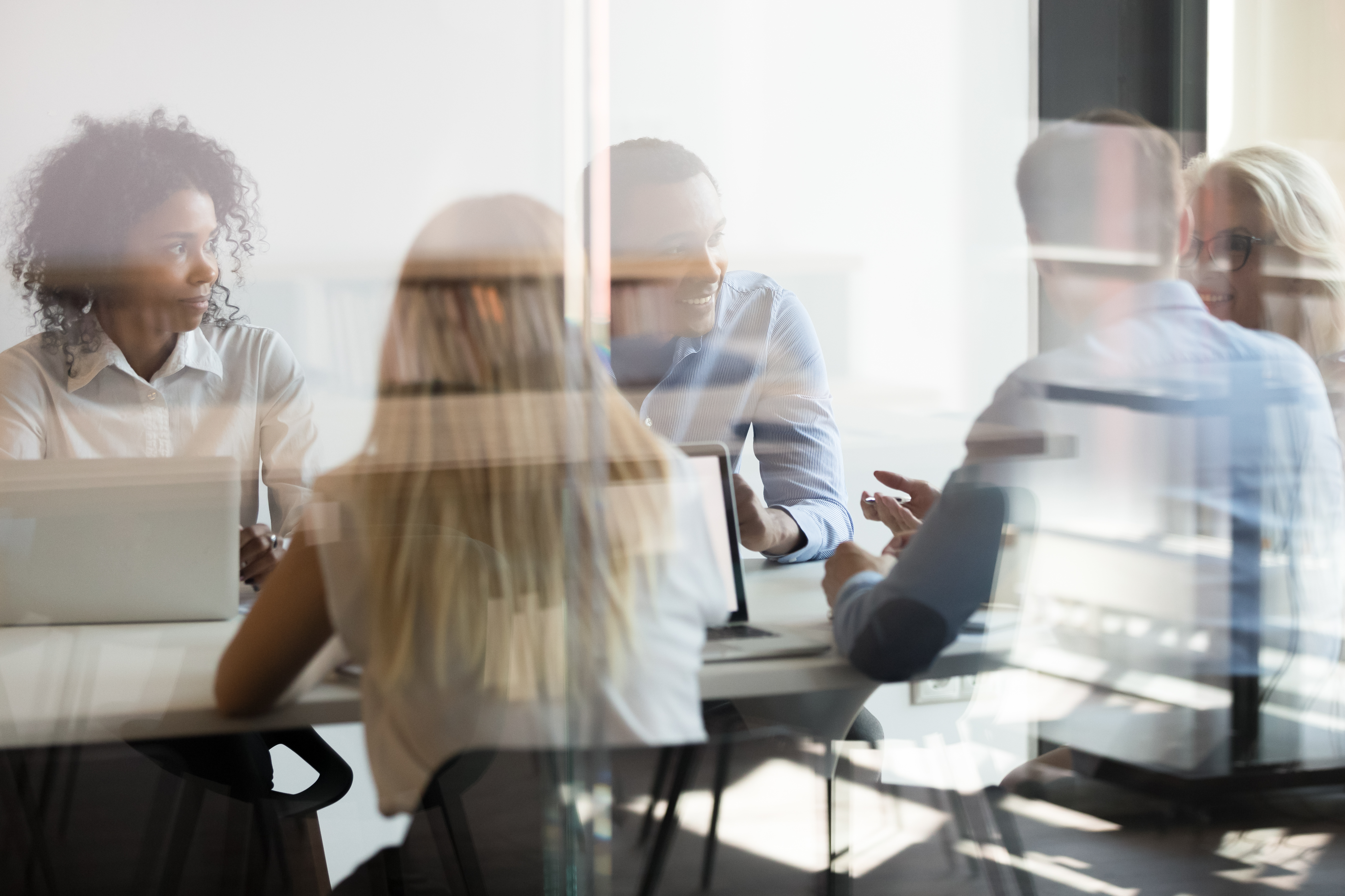 stylized image of a board room with people form diverse backgrounds sitting around a table