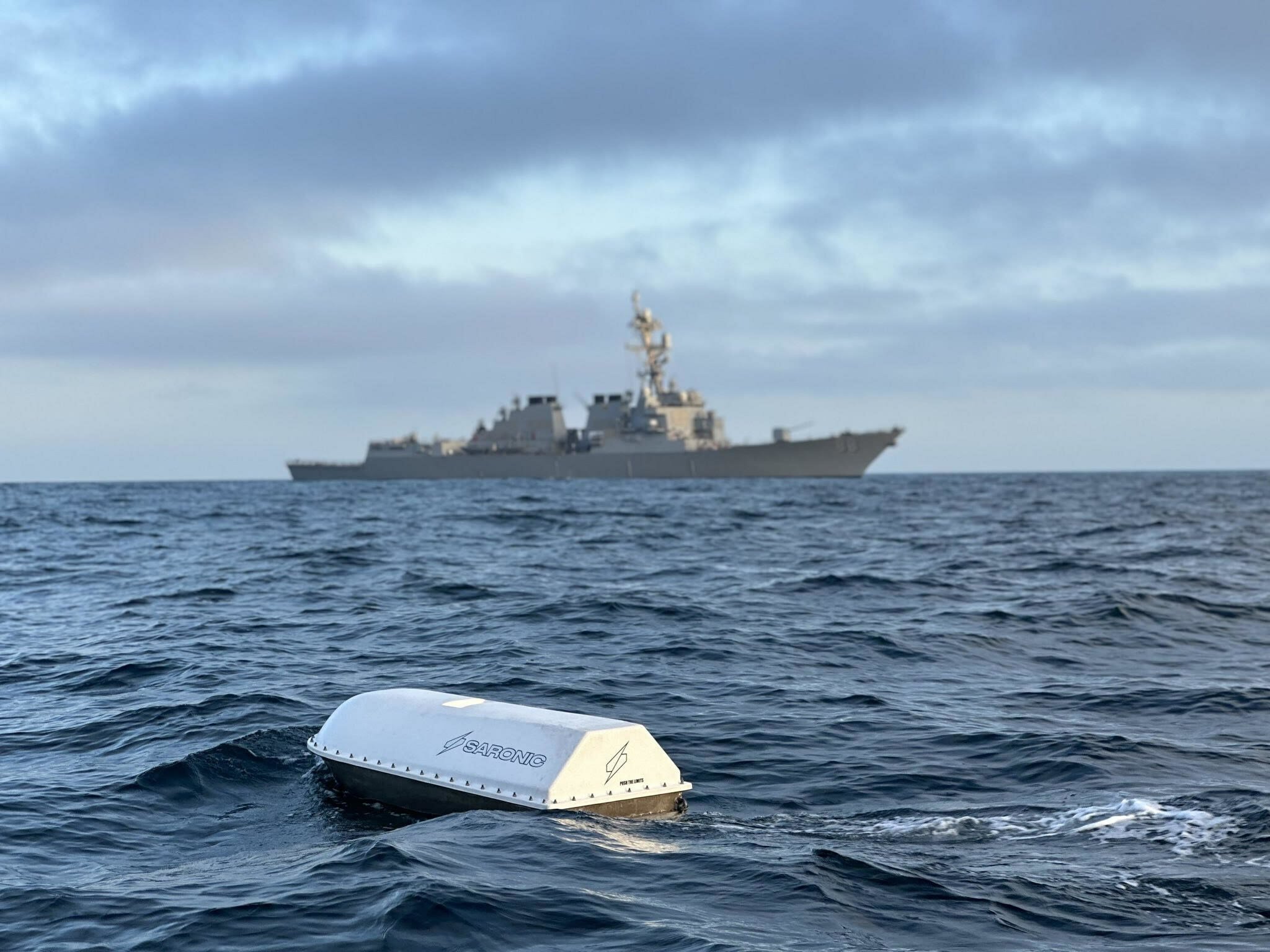 Saronic's Spyglass product sits in open water in front of a ship.