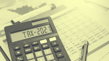 A yellow-toned image of a calculator displaying "TAX-2021." small-business-startup-tax-credit