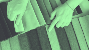 A green-toned image of two hands selecting fabric samples. what-is-data-fabric
