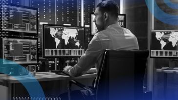 A cybersecurity professional works on multiple monitors