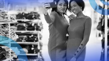 Two shoppers pose in matching dresses while using a phone.