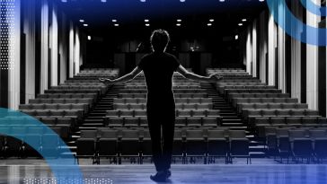 A performer stands onstage in front of an empty theatre