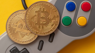 A game controller with cryptocurrency on top of it representing GameFi.