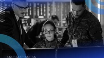 Three cybersecurity professionals work on a computer terminal