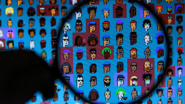 A person holding a magnifying glass to a screen filled with cryptopunks.