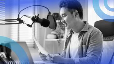 A young man sits in front of a microphone with a script in his hands. /marketing/podcast-that-gets-listeners