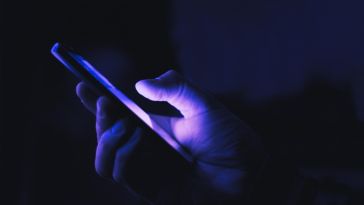 holding cellphone in dark lighting to illustrate shadowban