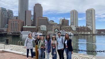 a group of seven people standing in front of Boston's harbor