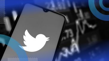 The Twitter logo on a smartphone in front of a stock ticker