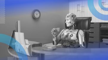 A robot drinks from a mug while sitting at a computer workstation