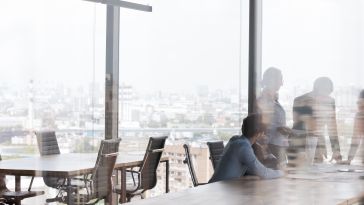 Office workers consult in a conference room overlooking a cityscape