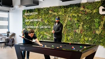 Photo of Demand.io team members playing pool in office near living wall