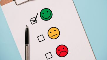 A pen lies on top of a survey that asks users to choose between a happy face, a neutral face and a sad face. This user has marked the happy face.