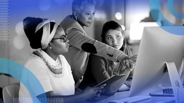 Three women working on a computer and tablet together.