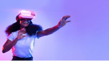 Excited young lady using VR glasses, touching something invisible, experiencing a virtual reality adventure on neon studio background.