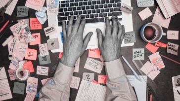 hands on a laptop surrounded by sticky notes