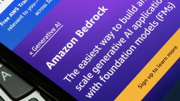A closeup photo of a smartphone resting on a computer keyboard, and on the smartphone screen it reads the Amazon Bedrock homepage