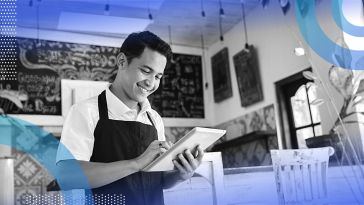 A coffee shop clerk looks at a tablet computer