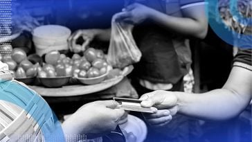 Two people exchanging a debit/credit card to purchase/sell fresh local tomatoes.