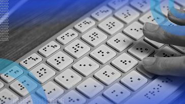 A hand typing on a braille computer keyboard.