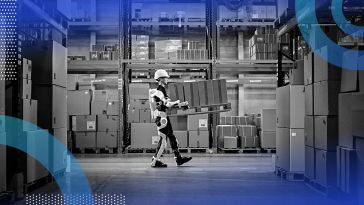 A man in a warehouse wearing a hardhat and robotic gear, which is helping him carry boxes.