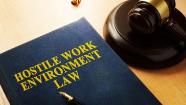 A textbook titled "Hostile Work Environment Law" is pictured on a desk next to a judge's gavel.