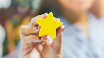 A hand holds up a gold star.