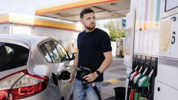  A man looks at a fuel pump display as he refuels his car.