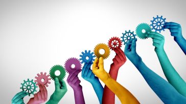 Hands of different vibrant hues hold interconnected gears.