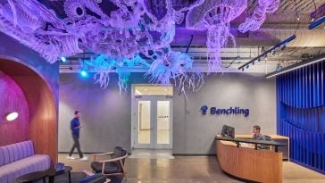 A photo of the Benchling office entryway, lit with purple light and decorated with an art installation that looks like jellyfish floating along the ceiling. 