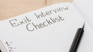 A pen lies on an empty notebook page titled "exit interview checklist."