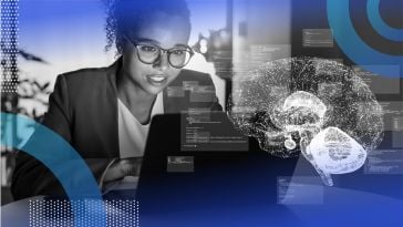 A Black woman with glasses works at a computer with a stylized image of a brain overlaid