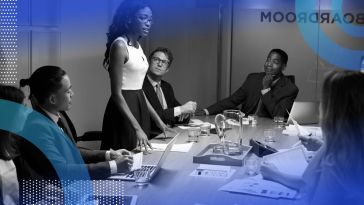 A Black woman is giving a presentation at a board meeting.