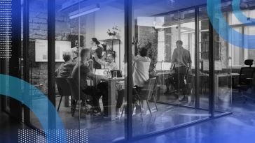 A group of tech employees celebrate in a glass conference room