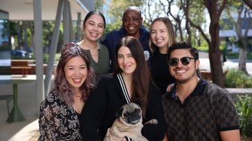 GoodRx smiling, posing for group photo on an outdoor patio, with one employee holding a dog in their arms