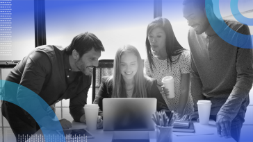 Diverse employees are gathered around a computer screen.