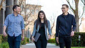 Nathan Dean walks with two Roblox teammates along an outdoor path next to office 