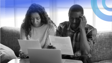 A Black couple looks frustrated as they review financial papers.