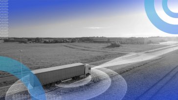 A semi-truck driving down a country road flanked by fields, with holographic circles around it and a holographic beam coming fromt the front.