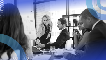 A saleswoman is making a presentation to people seated at a conference table.