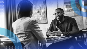 Two people are seated at a table having a conversation.