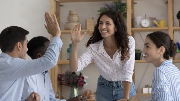 A team of sales professionals high-five in celebration.