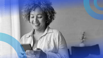 A woman smiling at her smart phone.