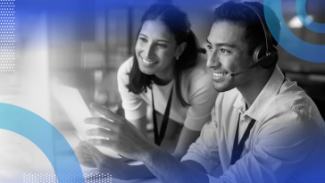 Two tech team members are smiling and looking at a computer screen.