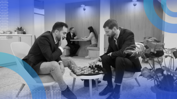 Two men play chess in an office