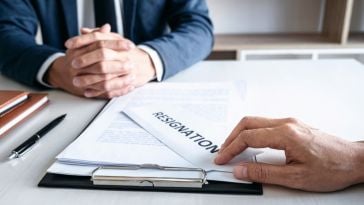 An employee places a resignation letter on their boss' desk.